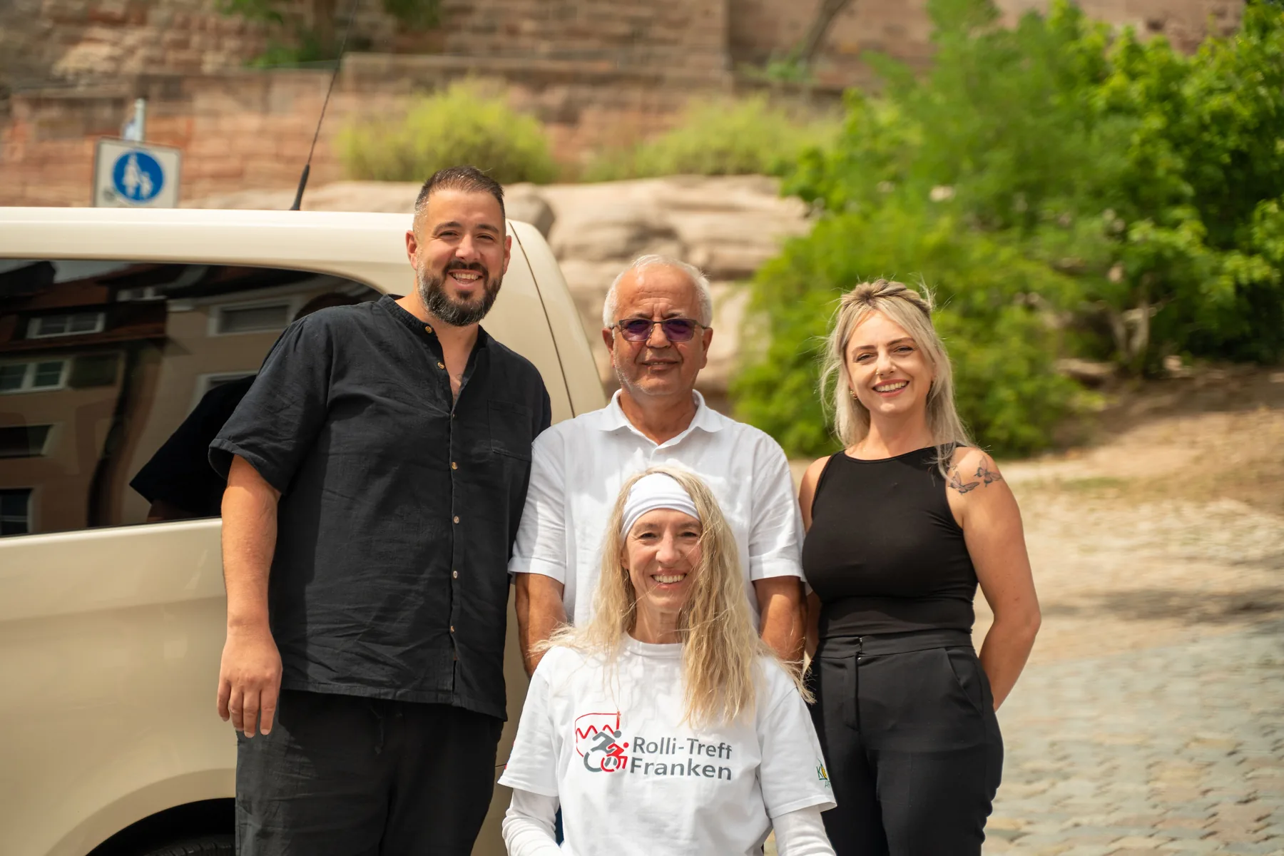 Das Handicap-Drive-Team gemeinsam mit einer Rollstuhlfahrerin vor dem Fahrzeug
